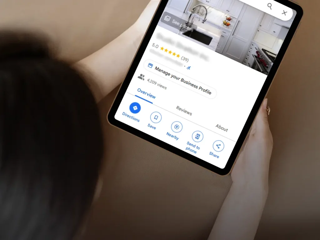 Person viewing a Google Business Profile on a tablet featuring a kitchen design listing with 5-star reviews and engagement details