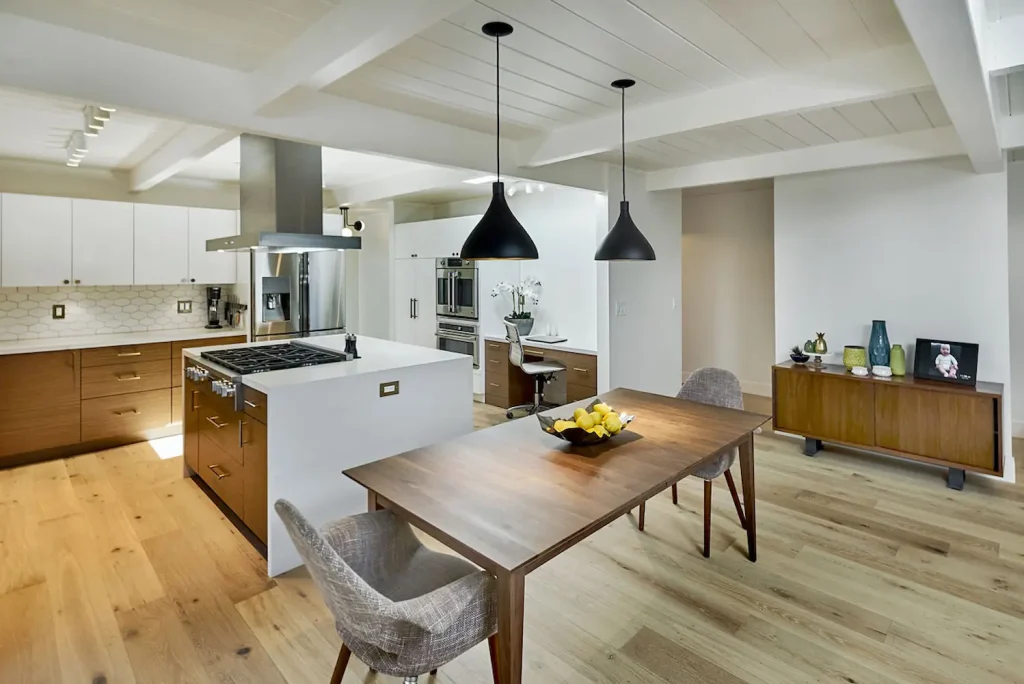 Modern kitchen with Crystal Cabinet Works cabinetry, featuring sleek wood finishes, white upper cabinets, a gas range, and an open dining area