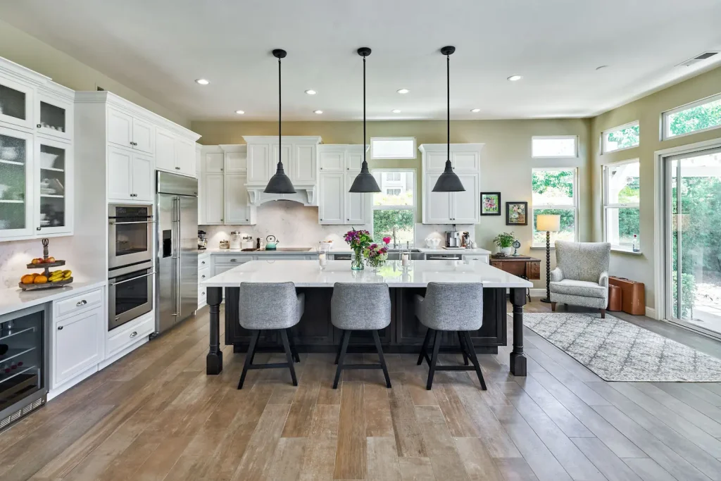 Traditional kitchen with Crystal Cabinet Works cabinetry, showcasing classic white cabinets, a large center island, and elegant pendant lighting