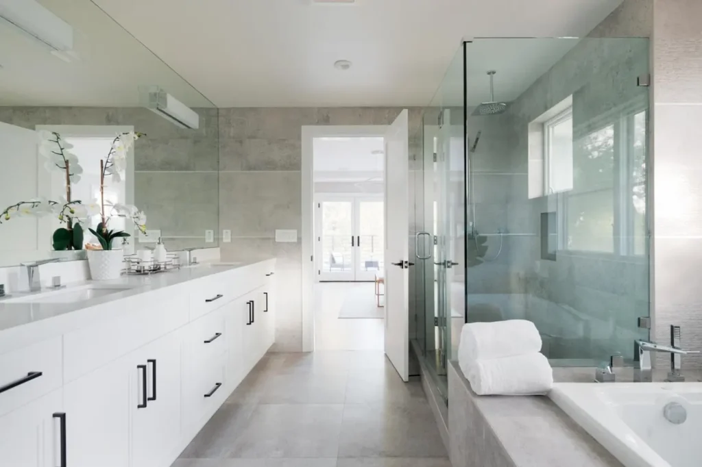 Bright and modern transitional bathroom with Crystal Cabinet Works cabinetry, featuring a sleek double vanity, a walk-in glass shower, and neutral-toned tile