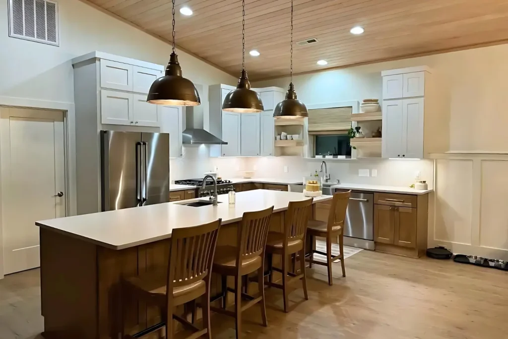 Farmhouse-style kitchen with wooden accents, white cabinetry, and pendant lighting illuminating a large island with seating