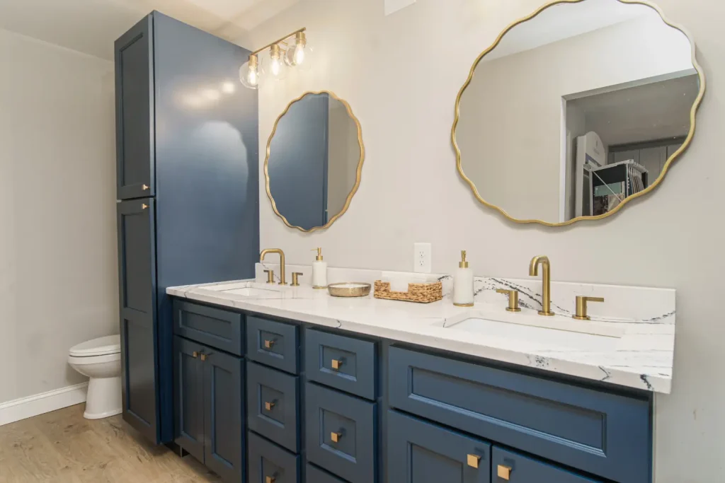 A navy blue bathroom vanity with double sinks, gold hardware, and two circular mirrors, creating a sophisticated look
