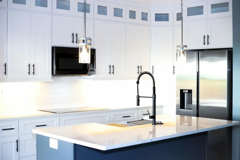 Modern kitchen with white shaker cabinets, a navy-blue island, stainless steel appliances, and a sleek black gooseneck faucet