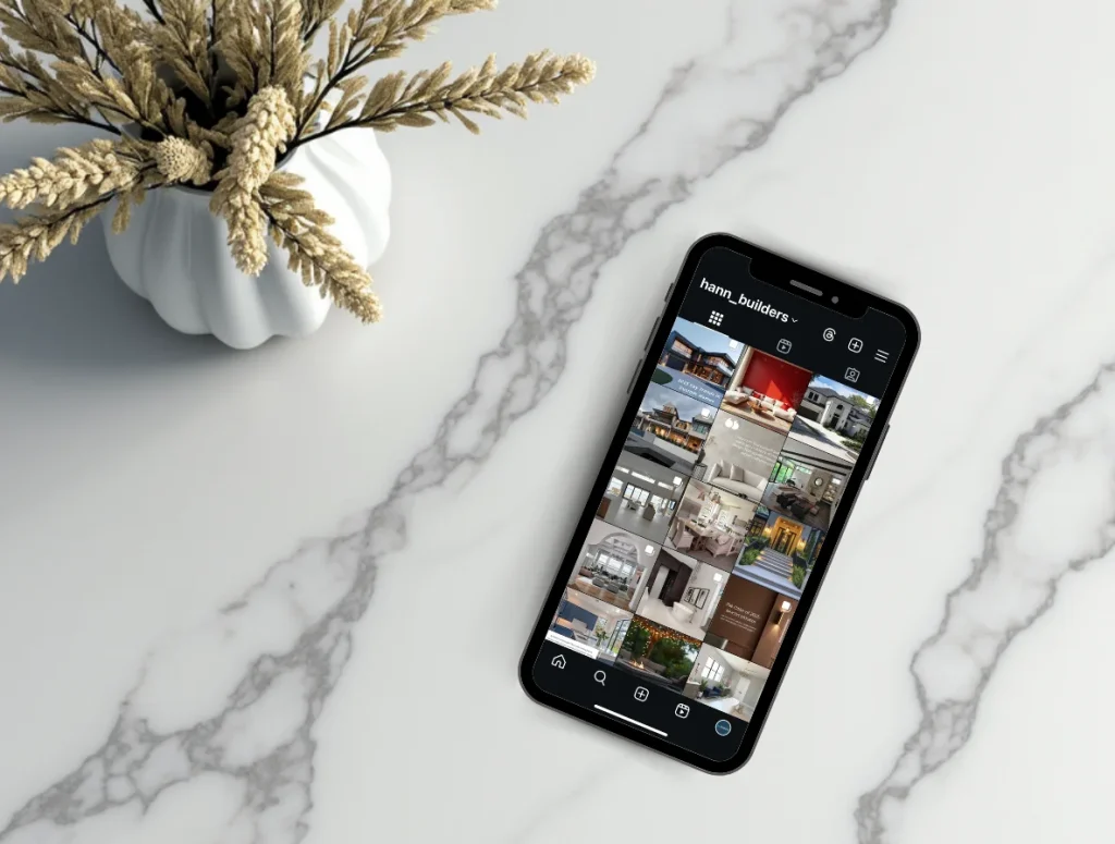 Mobile phone on a marble surface showing an Instagram profile filled with custom home designs, emphasizing strong online presence